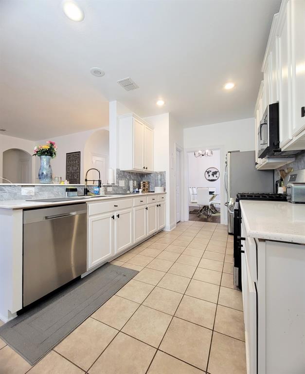 Kitchen featuring white shaker-style cabinetry, solid-surface countertops, stone-tile backsplash, stainless steel dishwasher, and recessed lighting Kitchen featuring white shaker-style cabinetry, solid-surface countertops, stone-tile backsplash, stainless steel dishwasher, and recessed lighting