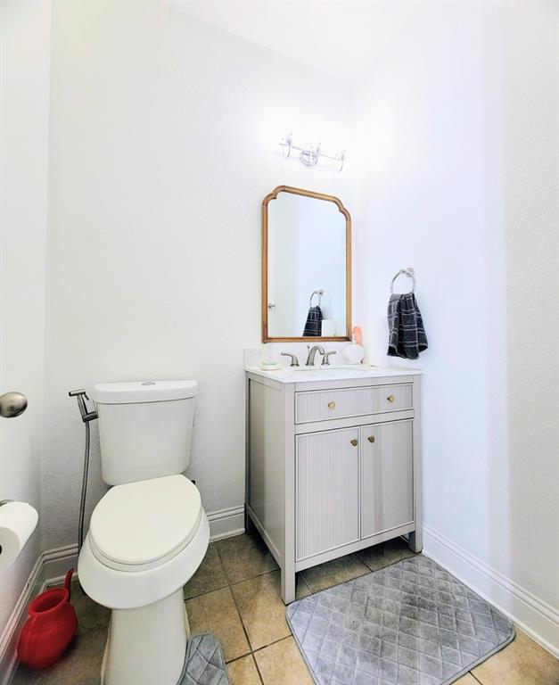 Light-toned vanity cabinet with stone-finish countertop, undermount sink, metallic hardware, and arched wall-mounted mirror Light-toned vanity cabinet with stone-finish countertop, undermount sink, metallic hardware, and arched wall-mounted mirror