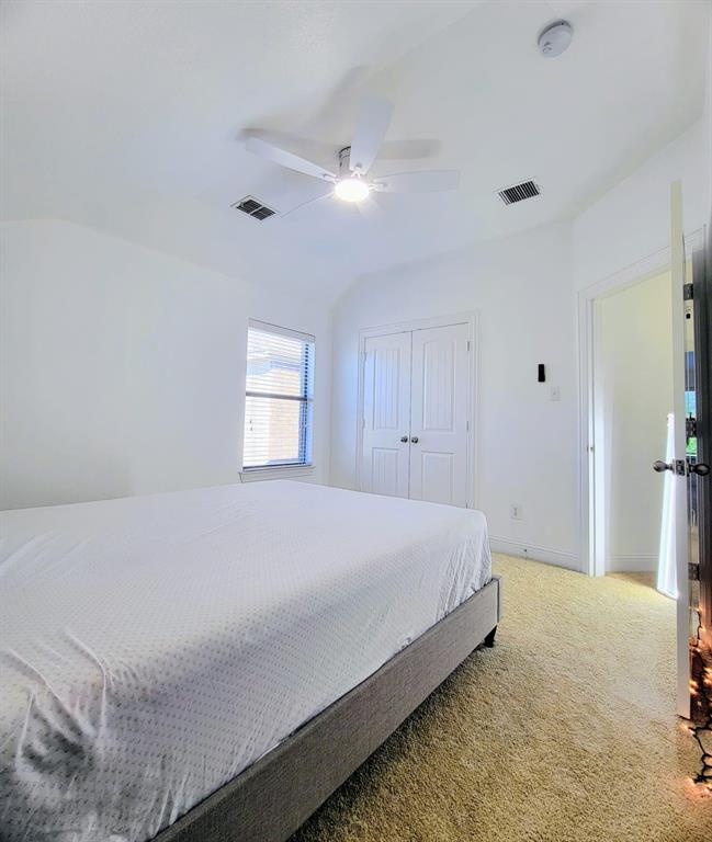 Room featuring vaulted ceilings, a central ceiling fan with integrated lighting, carpeted flooring, and a closet with double doors Room featuring vaulted ceilings, a central ceiling fan with integrated lighting, carpeted flooring, and a closet with double doors