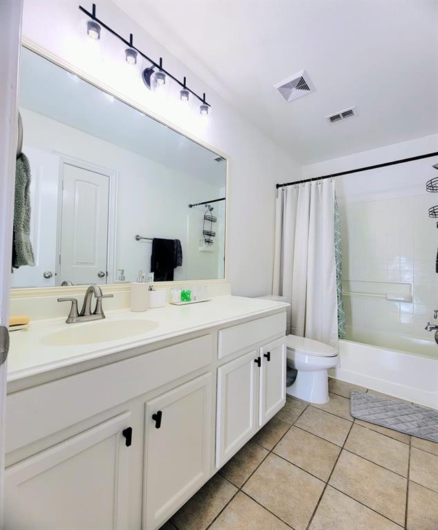 Bathroom featuring a vanity with white cabinetry, a large integrated countertop sink, a multi-bulb light fixture, a full-width mirror, and a tile floor