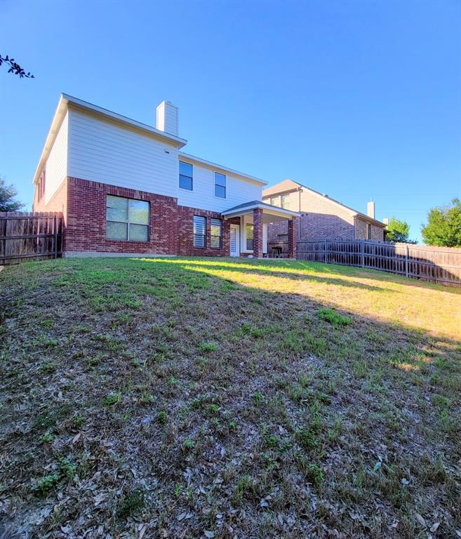 Two-story exterior featuring a brick and siding facade, covered rear patio, and fenced backyard