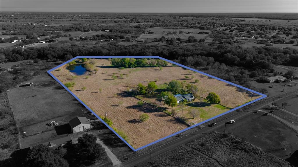 Expansive acreage featuring a private pond, mature trees, open pasture, and a detached outbuilding