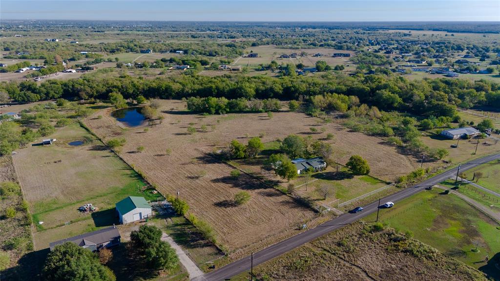 Expansive acreage featuring a private pond, mature trees, open pasture, and a detached metal-sided structure