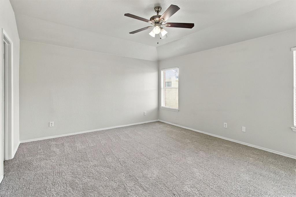 Room with high tray ceiling, neutral wall-to-wall carpeting, and a multi-blade ceiling fan with integrated lighting fixture