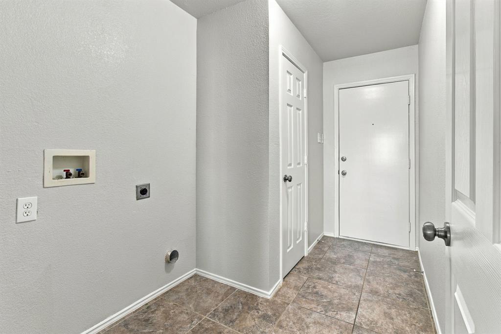Utility space featuring ceramic tile flooring, neutral wall paint, a recessed plumbing supply box, and two six-panel interior doors