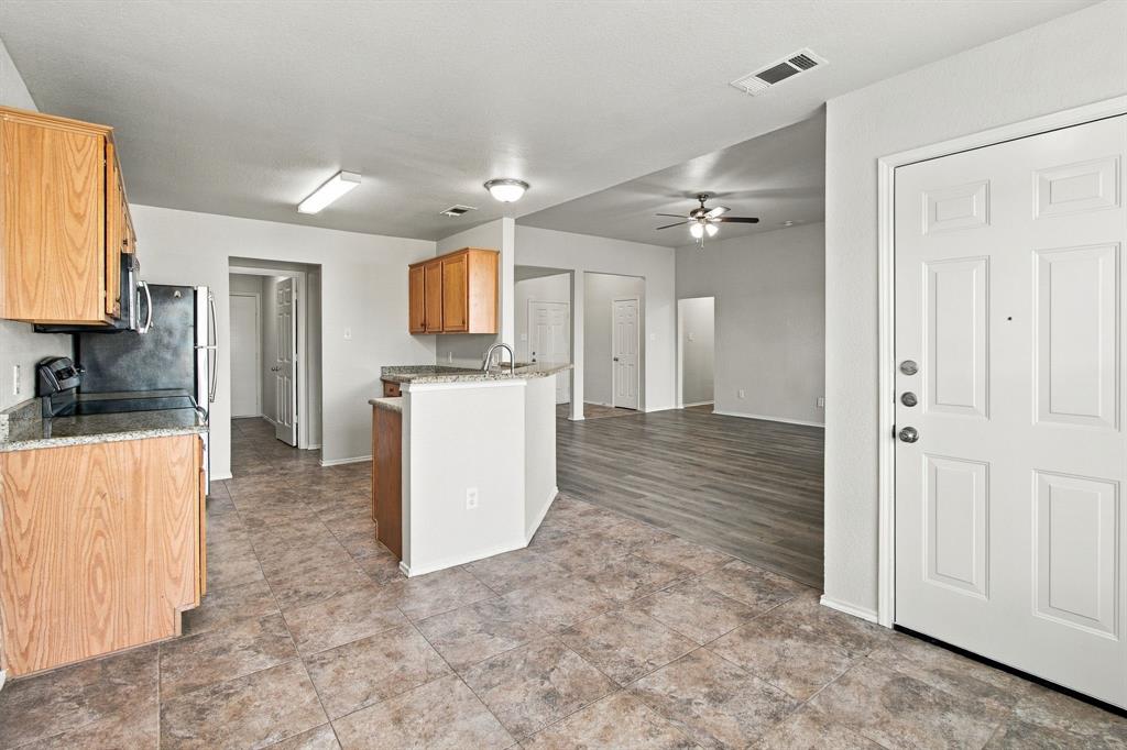 Kitchen featuring wood-finish cabinetry, stone-patterned countertops, tile flooring, and wood-finish flooring in the living area