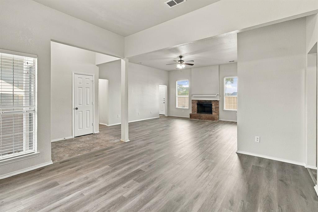Open concept floor plan featuring wood-finish flooring, a masonry fireplace, vaulted ceilings, and natural light from multiple windows Open concept floor plan featuring wood-finish flooring, a masonry fireplace, vaulted ceilings, and natural light from multiple windows