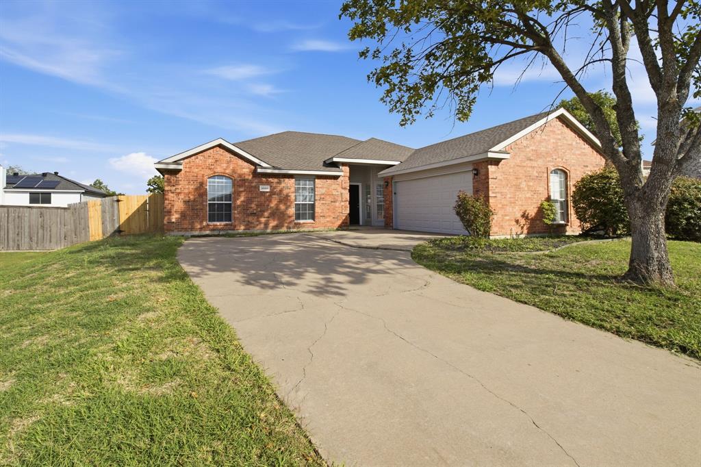 Single-story brick exterior featuring an arched window, asphalt shingle roof, concrete driveway, and attached garage