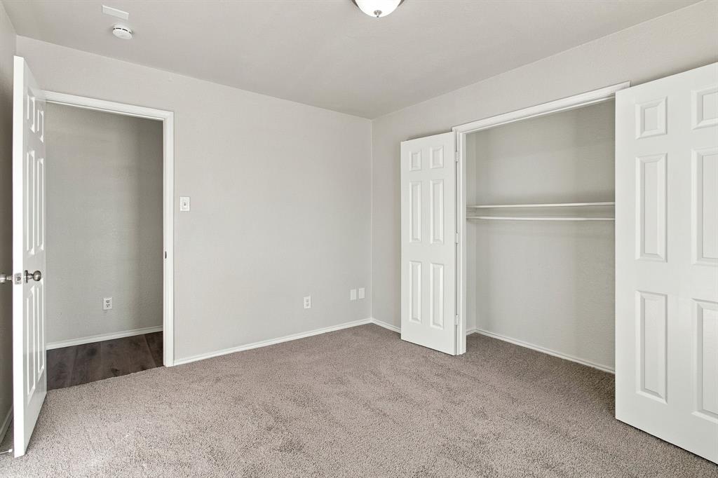 Neutral-toned room featuring neutral carpeting, six-panel interior doors, a closet with built-in shelving, and a dome ceiling light fixture