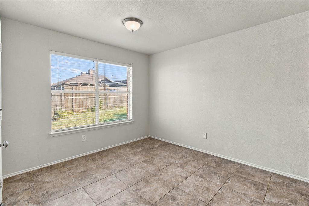 Neutral interior space featuring tile flooring, textured wall finish, and a large window with horizontal blinds
