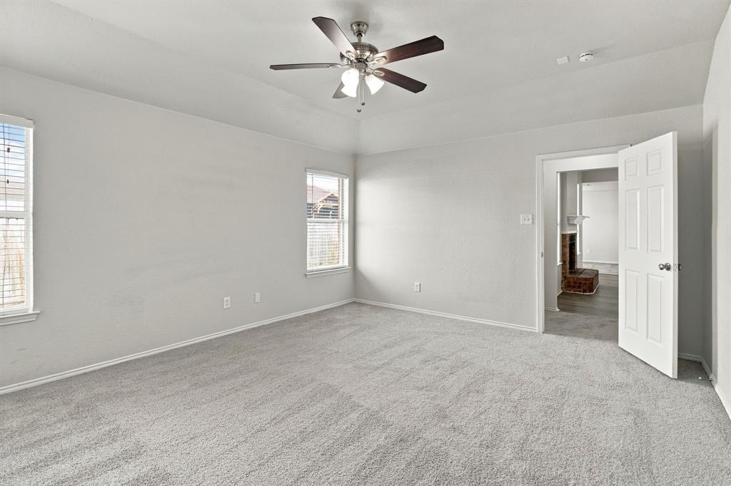 Tray ceiling with a central brushed-nickel ceiling fan, neutral wall-to-wall carpeting, and double-hung windows