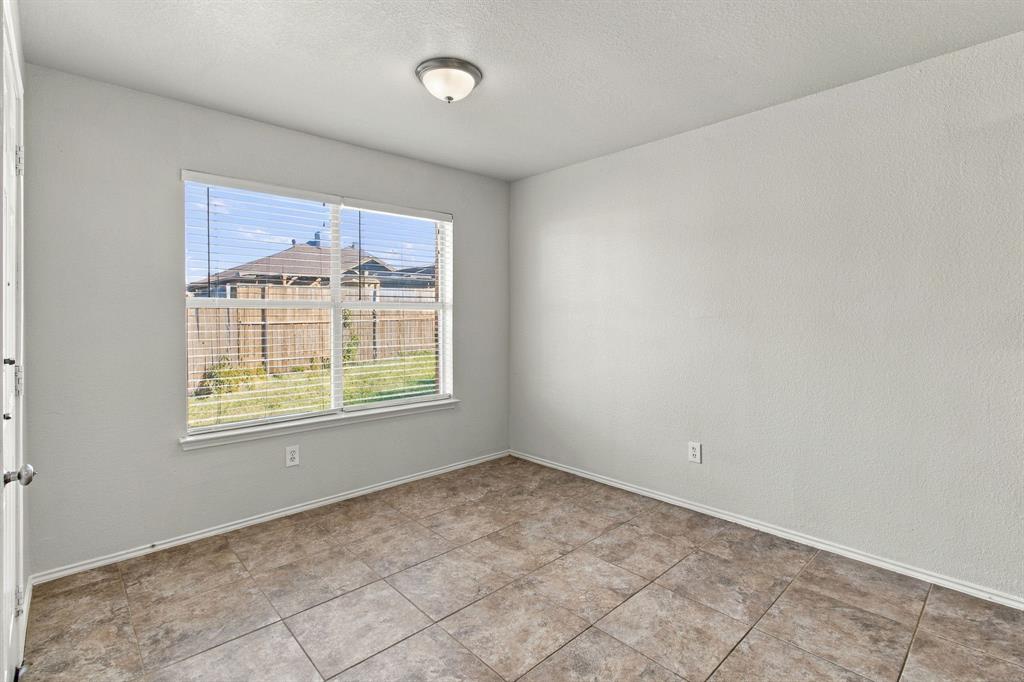 Neutral interior room featuring tile flooring, smooth-textured walls, a large window, and a flush-mount ceiling light fixture