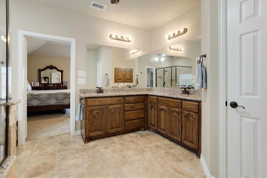 Bathroom vanity featuring dual sinks with granite countertops and wood cabinetry