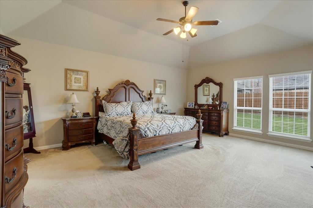 Spacious room featuring vaulted ceilings, neutral-toned carpeting, and a ceiling fan with integrated lighting