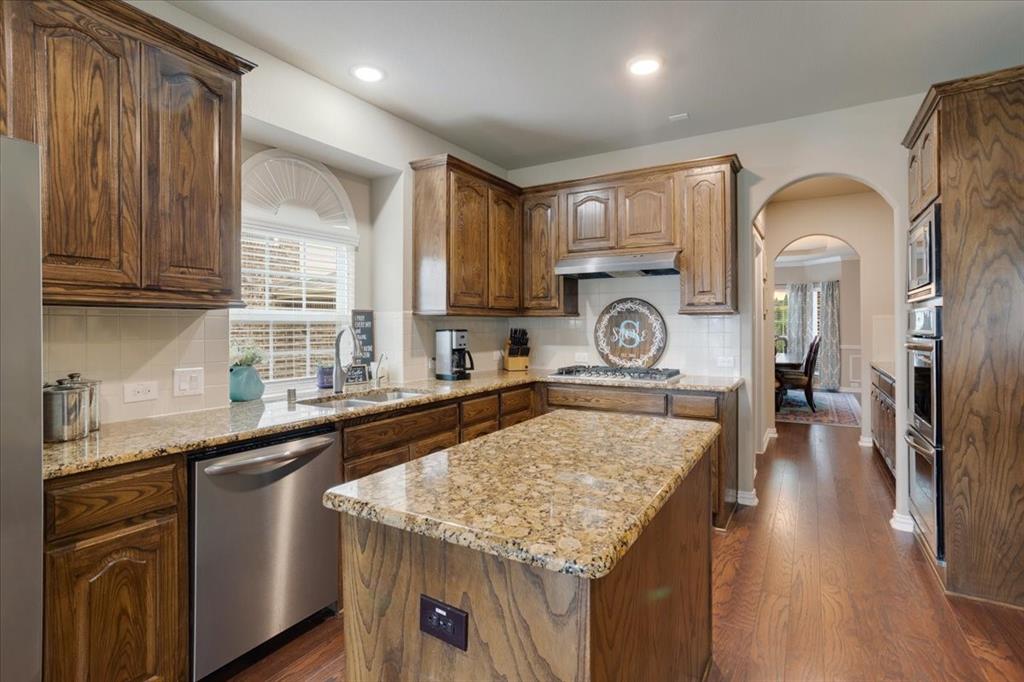 Kitchen featuring a central island with a granite countertop, wood-finish flooring, recessed lighting, and stainless steel appliances