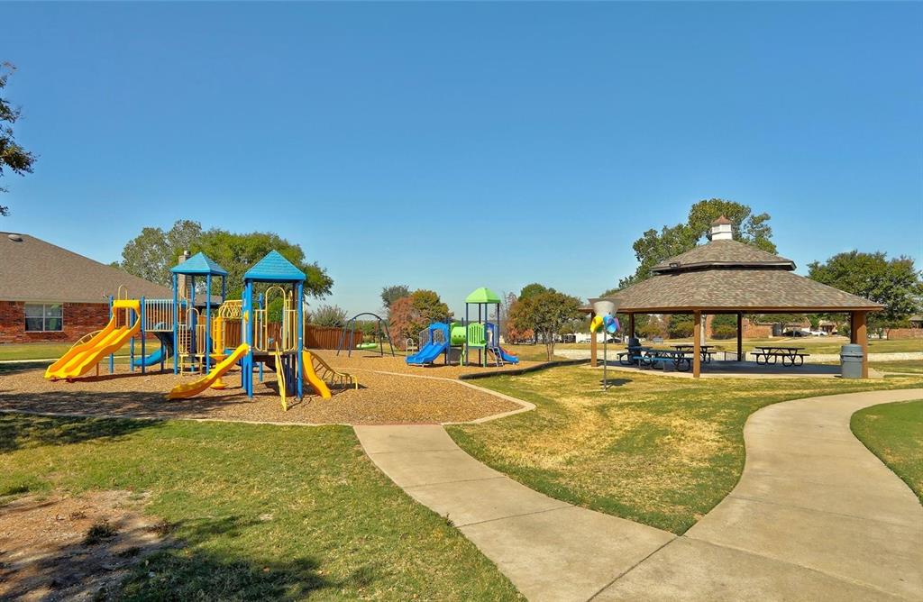 Community park featuring a multi-level playground, covered gazebo with picnic tables, walking paths, and expansive grassy areas