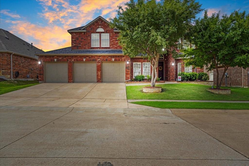 Brick exterior residence featuring a three-car garage, concrete driveway, and established front landscaping