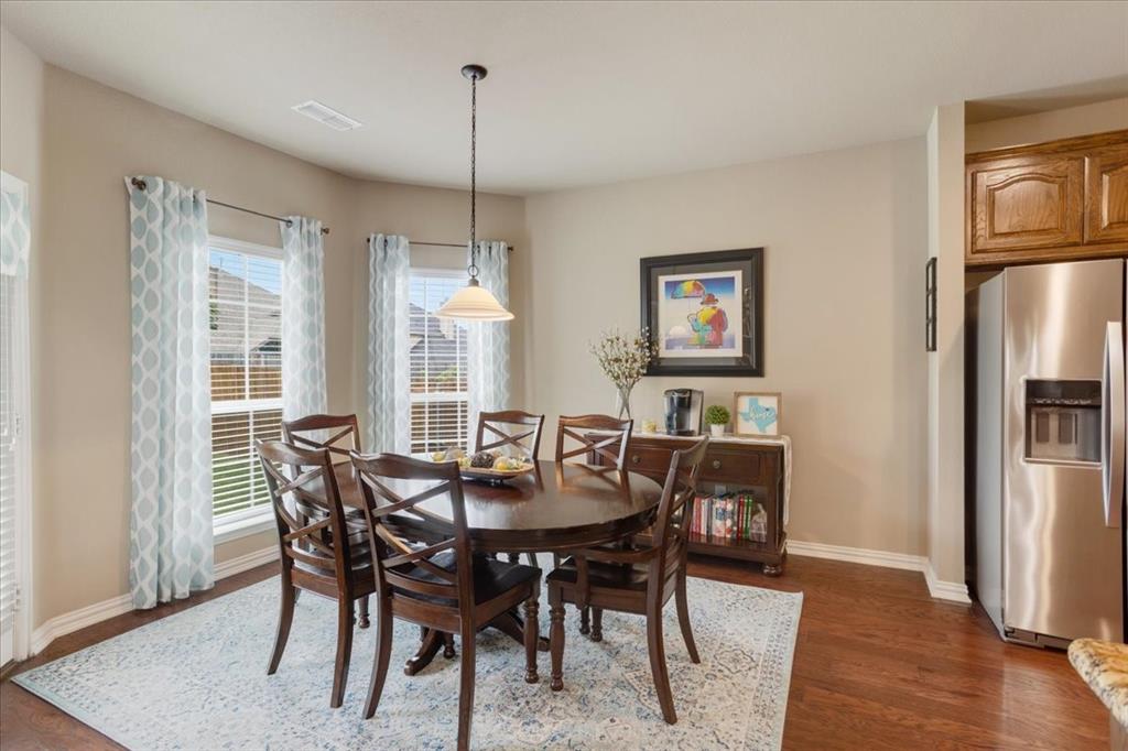 Dining area featuring a bay window, wood-finish flooring, and a contemporary pendant light fixture