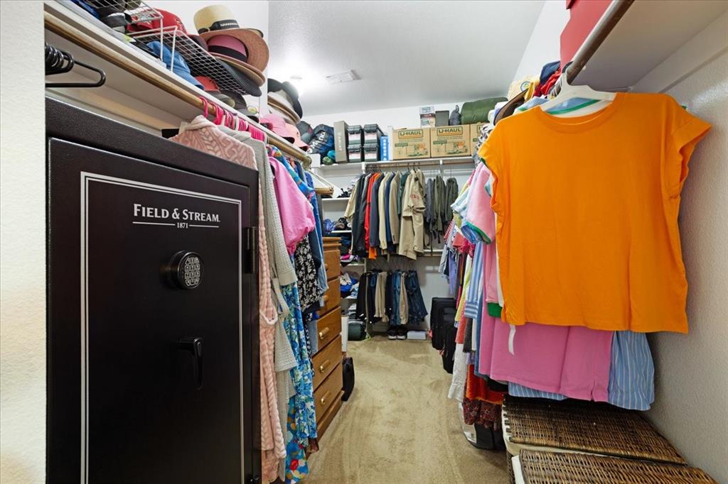 Spacious walk-in closet featuring wood-finish flooring, built-in shelving, and multiple clothing rods
