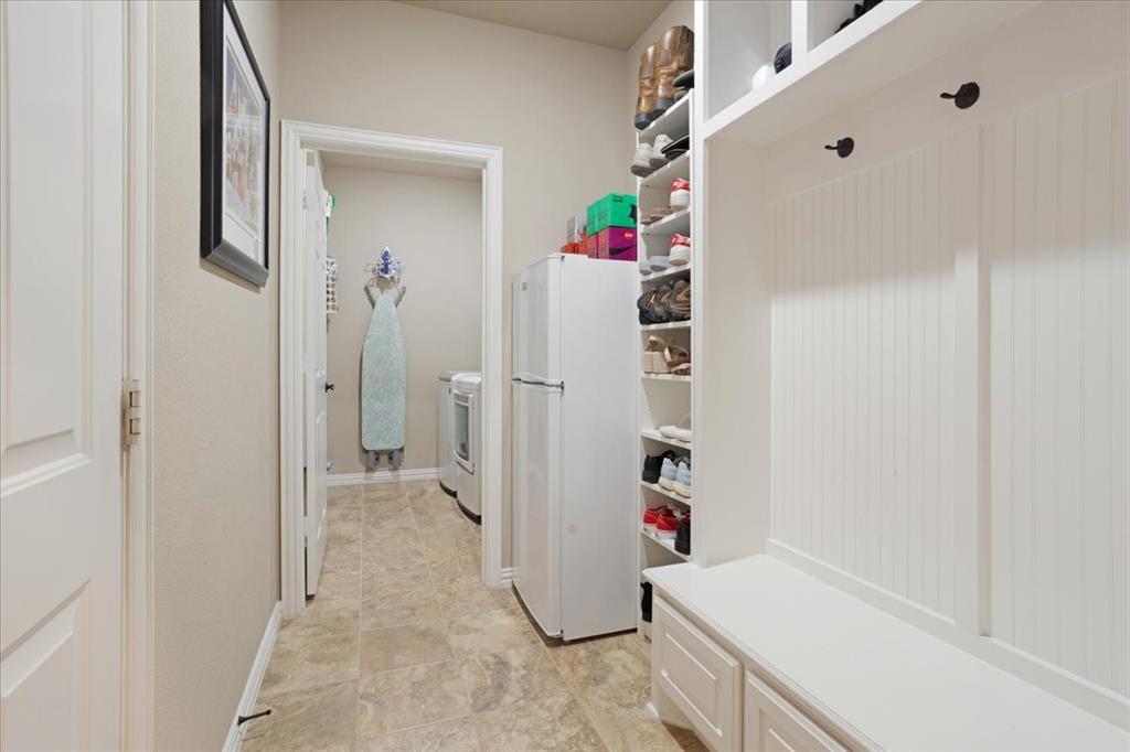 Entryway mudroom featuring built-in storage with open shelving, integrated bench seating with cabinet storage, and beadboard paneling