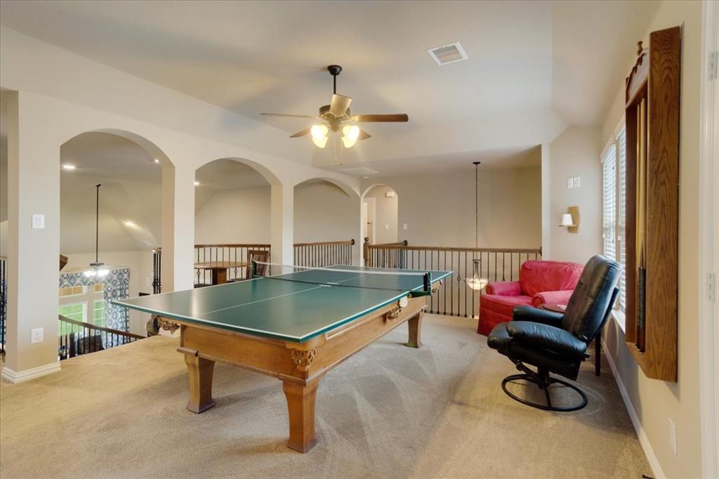 Carpeted loft area featuring multiple arched openings, a ceiling fan with integrated lighting, recessed lighting, and a balustrade overlooking the level below
