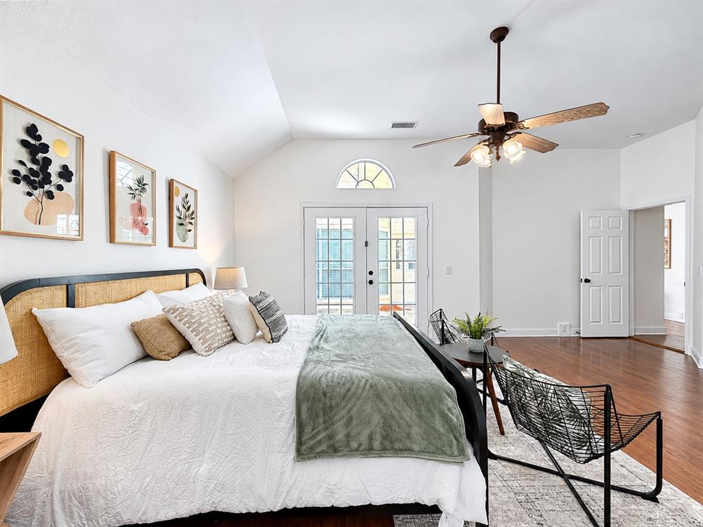 Vaulted ceilings, wood-finish flooring, French doors with an arched transom window, and a multi-blade ceiling fan with integrated lighting