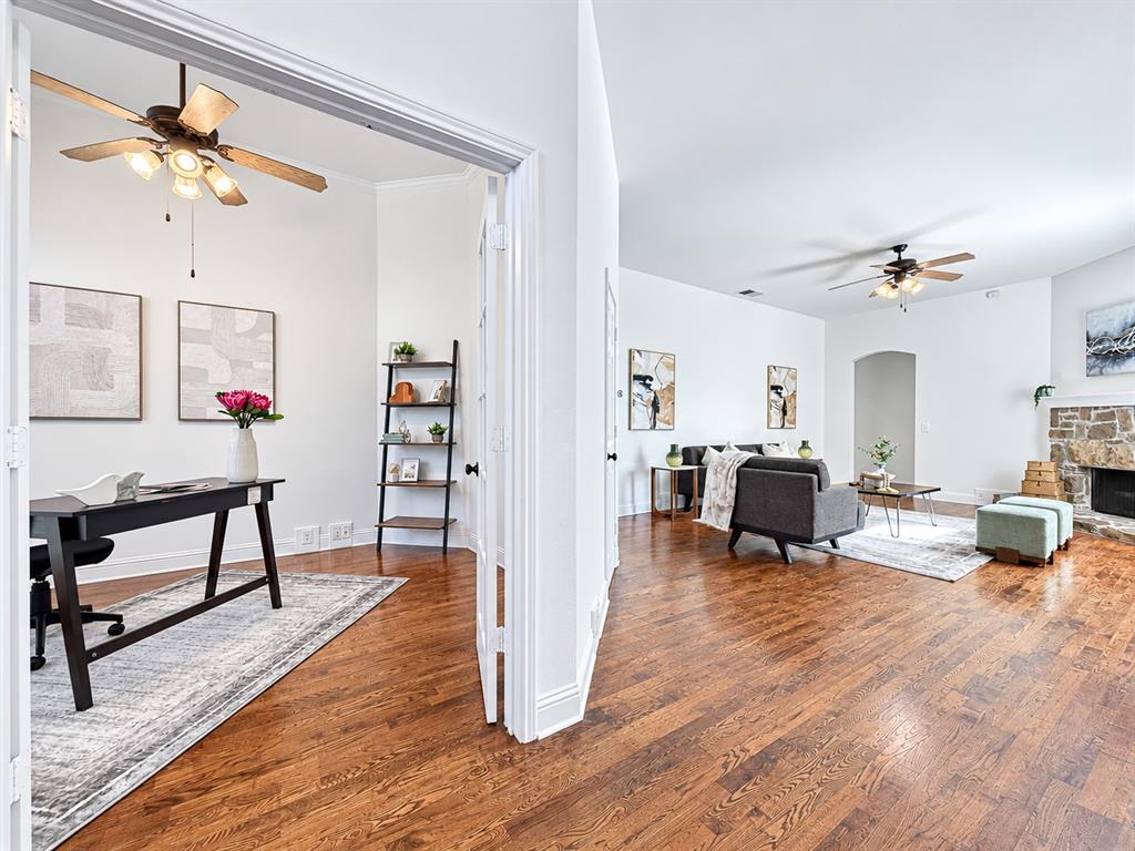 Wood-finish flooring, stone-surround fireplace, multi-light ceiling fans, and French doors