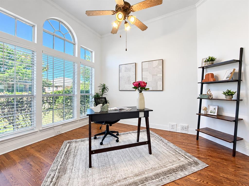 Room featuring expansive arched windows, wood-finish flooring, and a multi-light ceiling fan