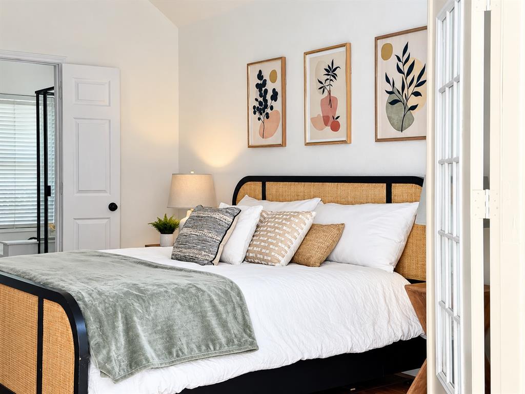 Vaulted ceiling, paneled door with round matte black hardware, and multi-light French door