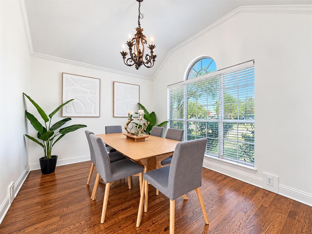 Vaulted ceilings, wood-finish flooring, ornate iron chandelier, and large window with an arched transom