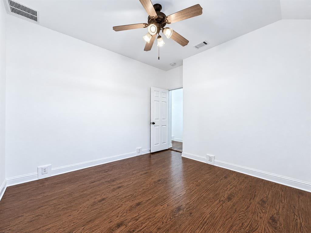 Room featuring wood-finish flooring, a multi-blade ceiling fan with integrated lighting, and a six-panel interior door