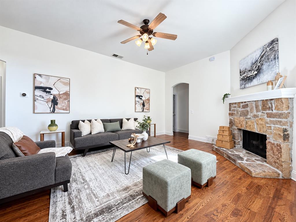 Living area featuring wood-finish flooring, vaulted ceilings, and a floor-to-ceiling stone fireplace with a white mantel