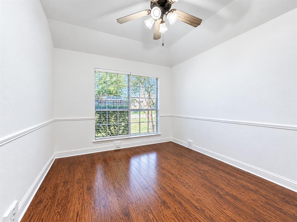 Room featuring wood-finish flooring, tray ceiling, chair rail molding, and a ceiling fan with integrated lighting