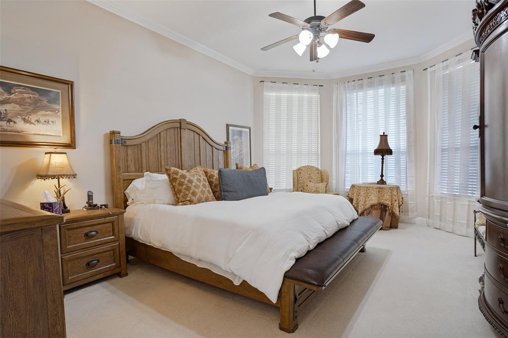Room featuring a bay window, ceiling fan with integrated lighting, neutral wall-to-wall carpeting, and crown molding
