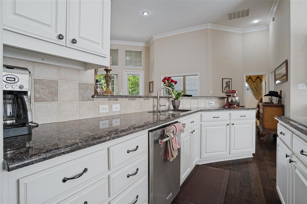 Kitchen featuring white cabinetry, dark stone countertops, stainless steel dishwasher, square-tile backsplash, and dark wood-finish flooring