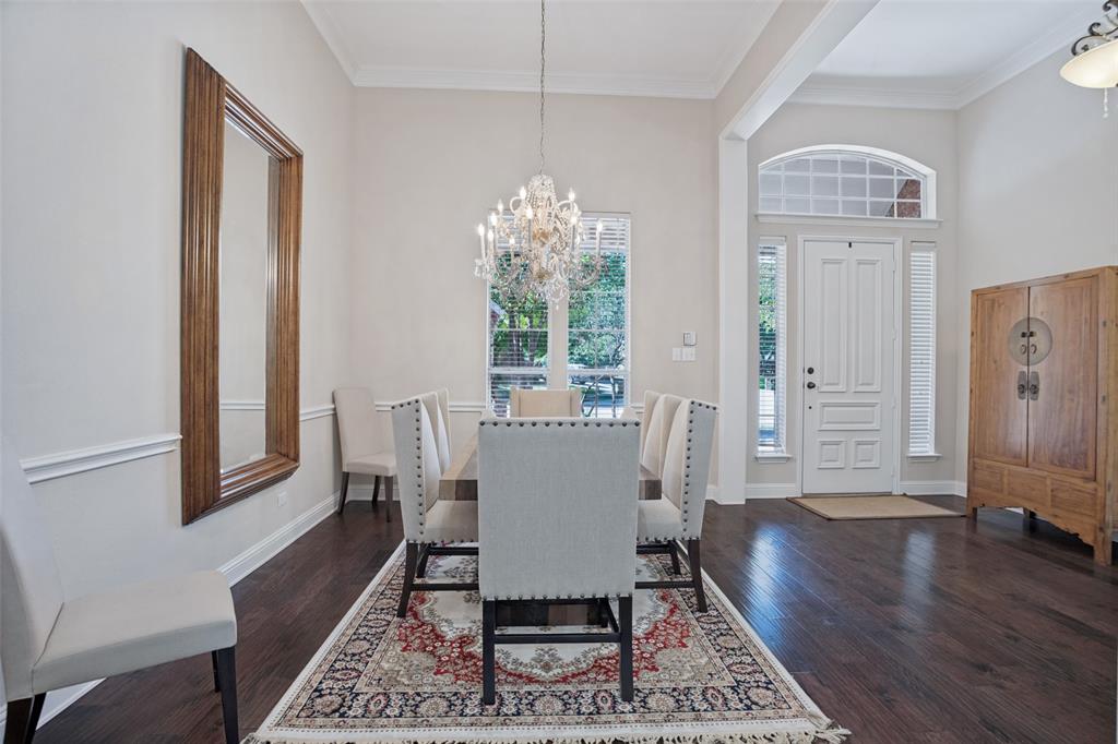 Formal dining area featuring dark wood-finish flooring, a decorative chandelier, wainscoting, and a panelled front door with an arched transom window