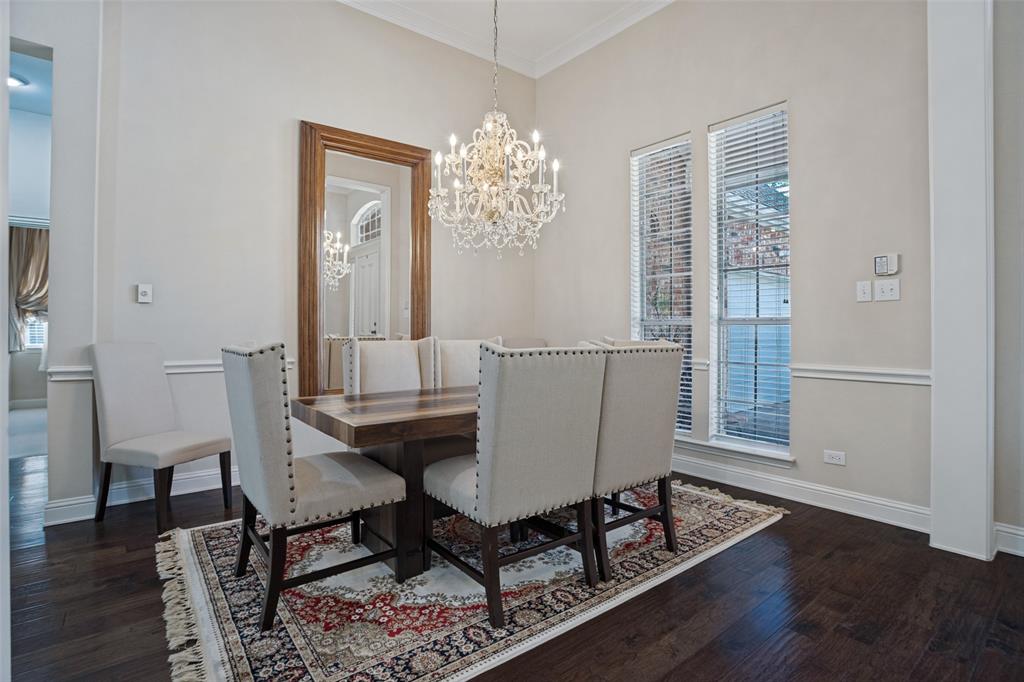 Dining area featuring wood-finish flooring, a decorative crystal chandelier, chair rail molding, and tall windows with horizontal blinds