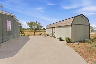 Concrete patio area featuring a detached storage building with a metal roof and exterior siding Concrete patio area featuring a detached storage building with a metal roof and exterior siding