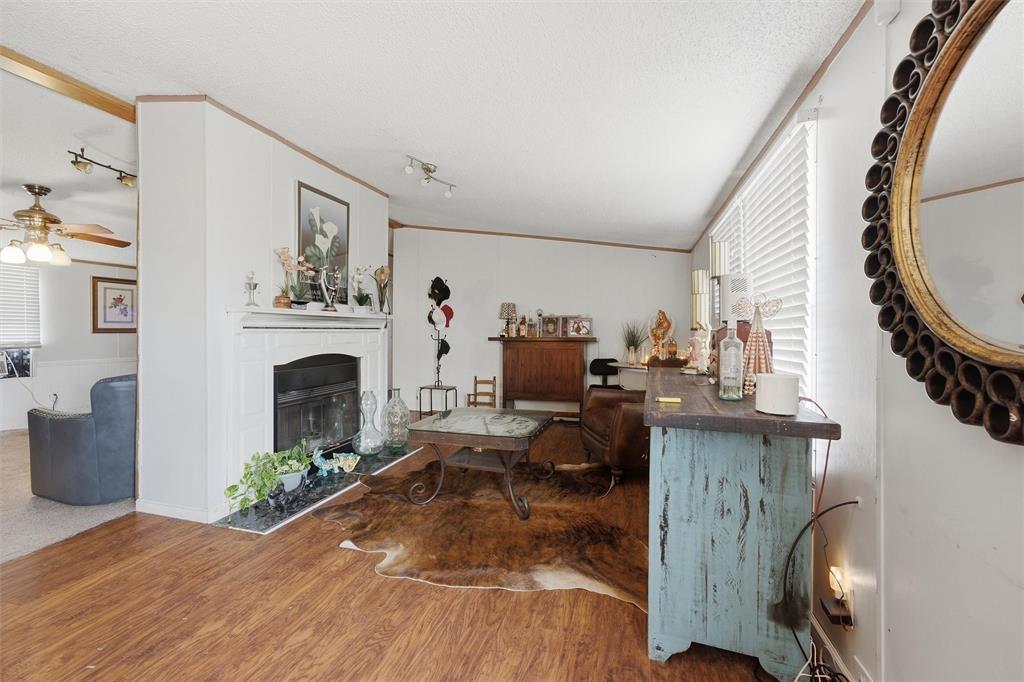 Wood-finish flooring, fireplace with a white mantel, stone-tile hearth, and track lighting Wood-finish flooring, fireplace with a white mantel, stone-tile hearth, and track lighting
