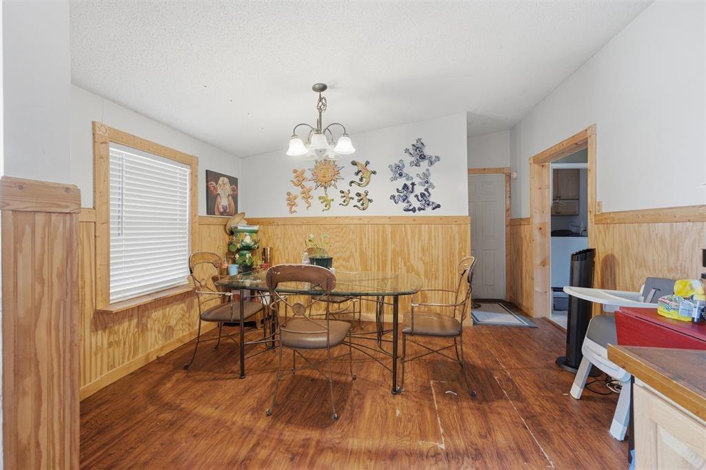 Wood-finish flooring, wood wainscoting, and a multi-arm overhead light fixture Wood-finish flooring, wood wainscoting, and a multi-arm overhead light fixture