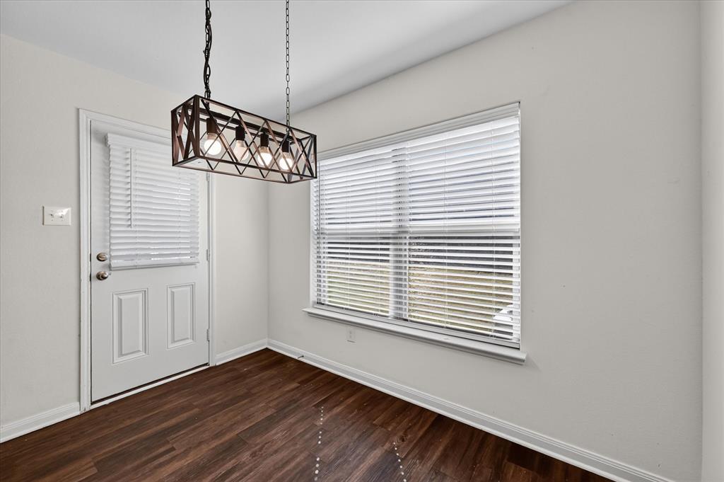 Rectangular four-light caged chandelier with a metal finish, wood-finish flooring, dual-pane window with integrated blinds, and glass-paneled exterior door Rectangular four-light caged chandelier with a metal finish, wood-finish flooring, dual-pane window with integrated blinds, and glass-paneled exterior door