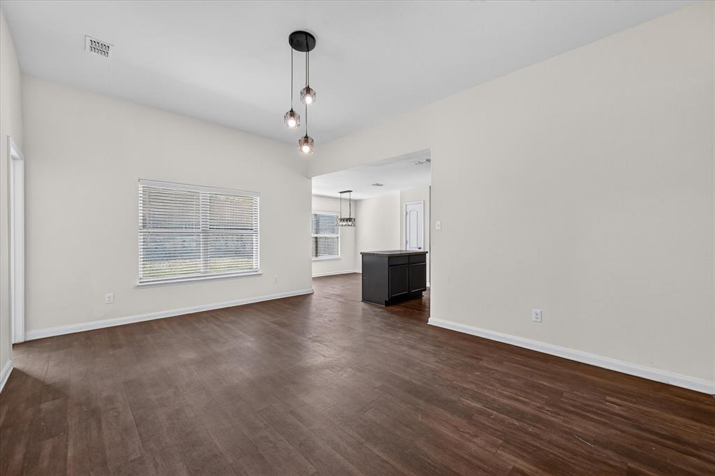 Interior space featuring high ceilings, wood-finish flooring, a multi-light pendant fixture, and large windows with horizontal blinds Interior space featuring high ceilings, wood-finish flooring, a multi-light pendant fixture, and large windows with horizontal blinds