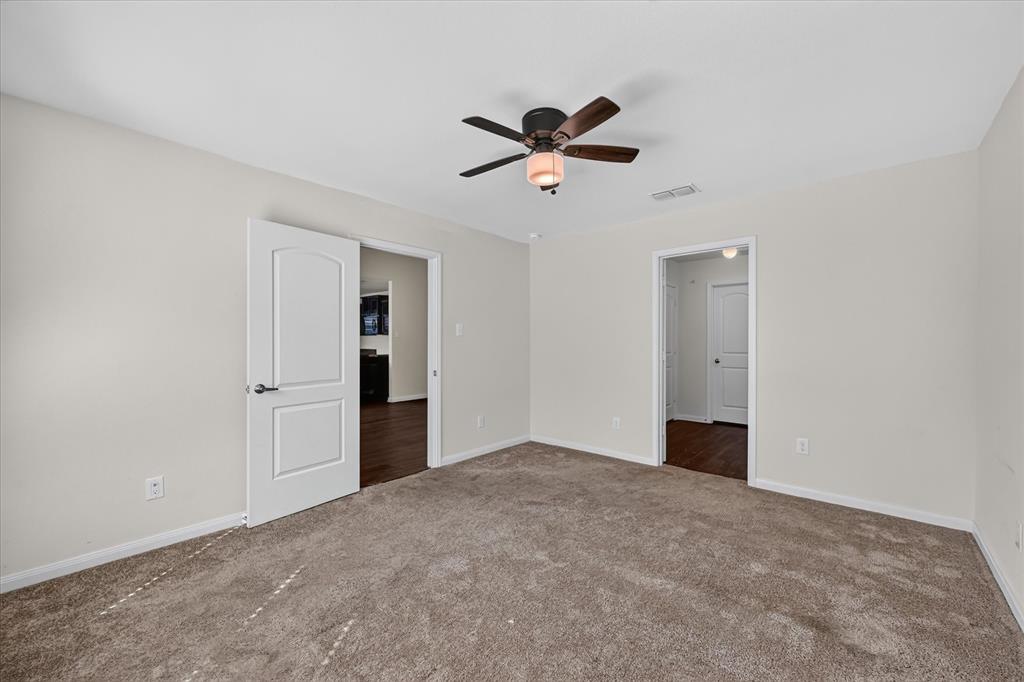 Interior space featuring neutral wall tones, plush wall-to-wall carpeting, a multi-blade ceiling fan with a centered light fixture, and arched-panel interior doors