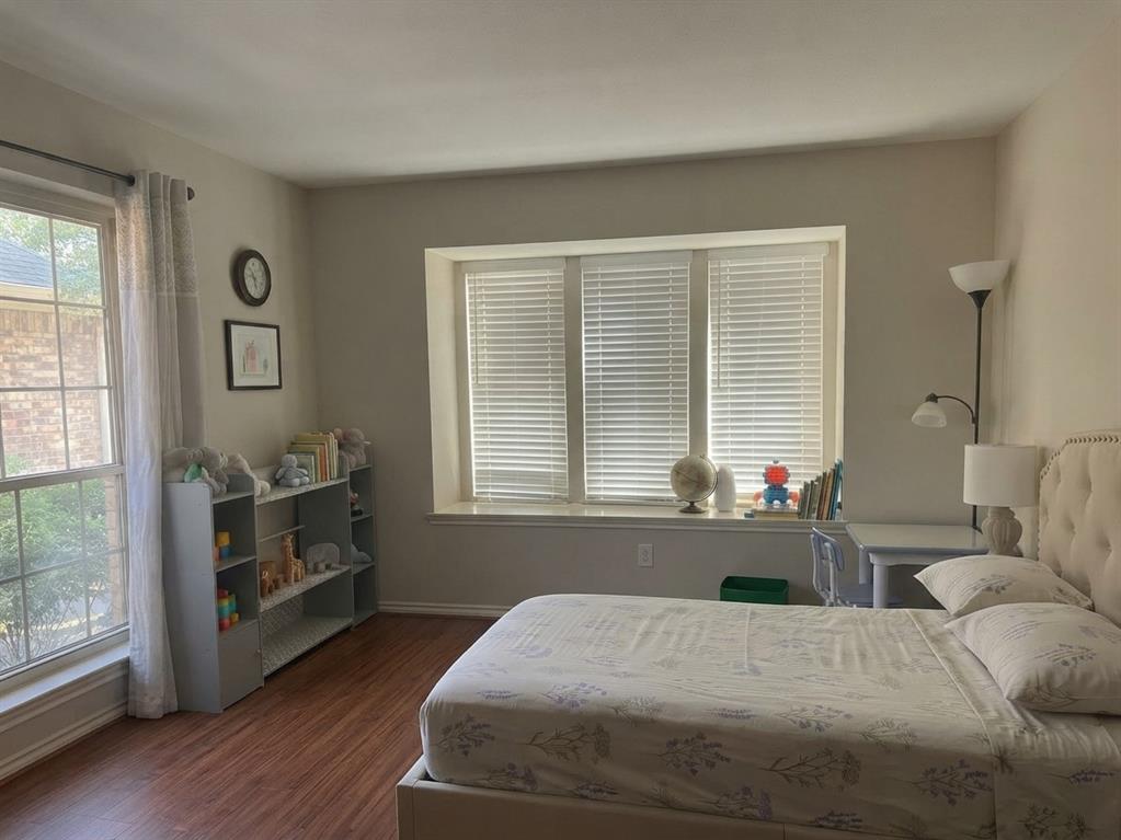 Wood-finish flooring, recessed window alcove with integrated sill, and two sets of windows featuring horizontal blinds