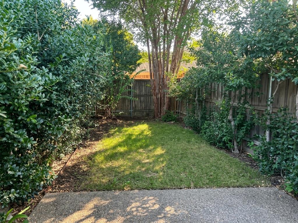 Rear yard featuring a concrete patio, perimeter wood fencing, and mature landscaping