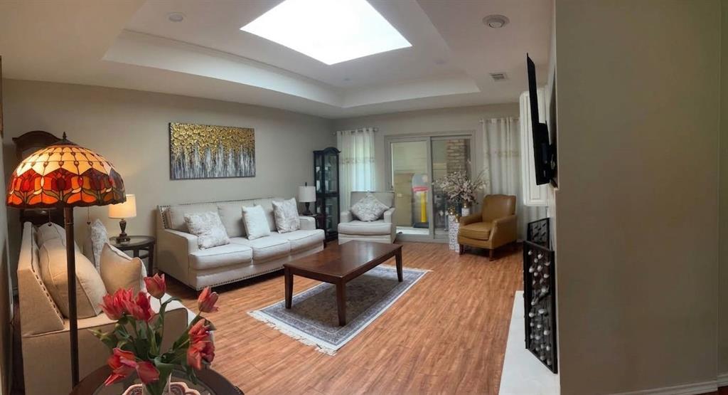 Tray ceiling featuring a central skylight, wood-finish flooring, sliding glass doors, and a fireplace surround