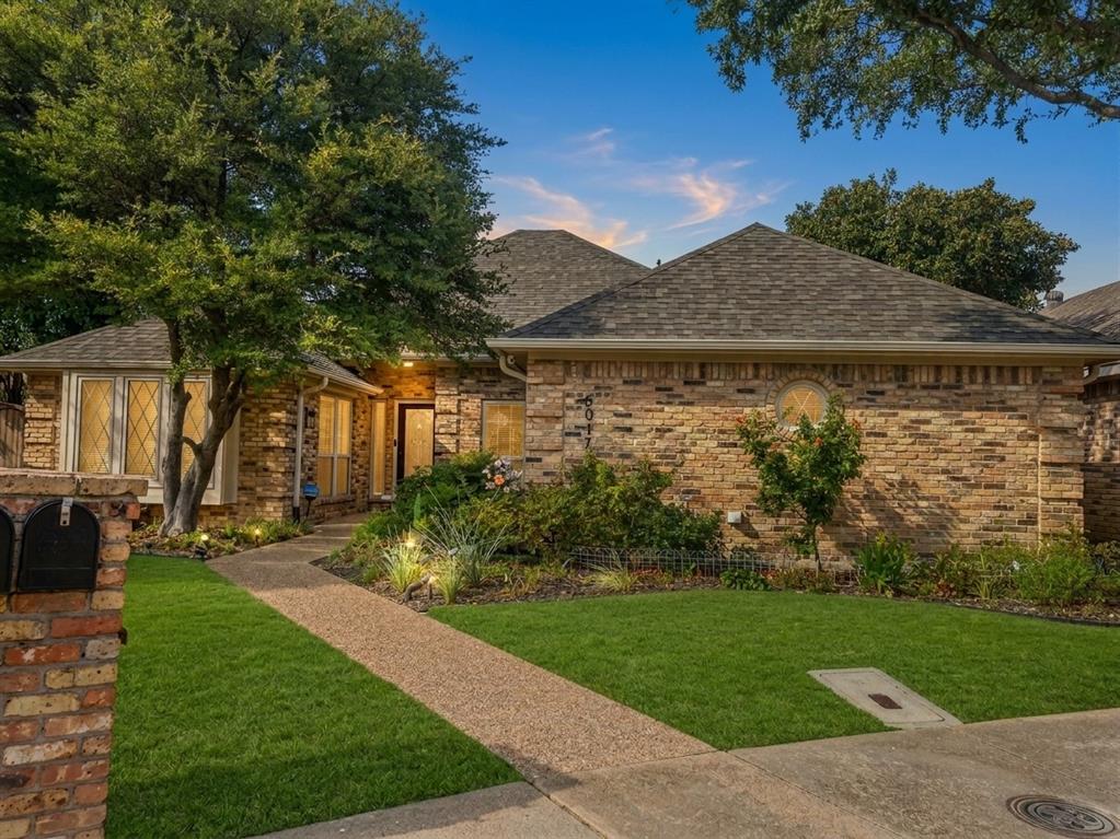 Brick exterior facade featuring a multi-gabled roofline, diamond-patterned window panes, a decorative circular accent window, and a finished masonry mailbox