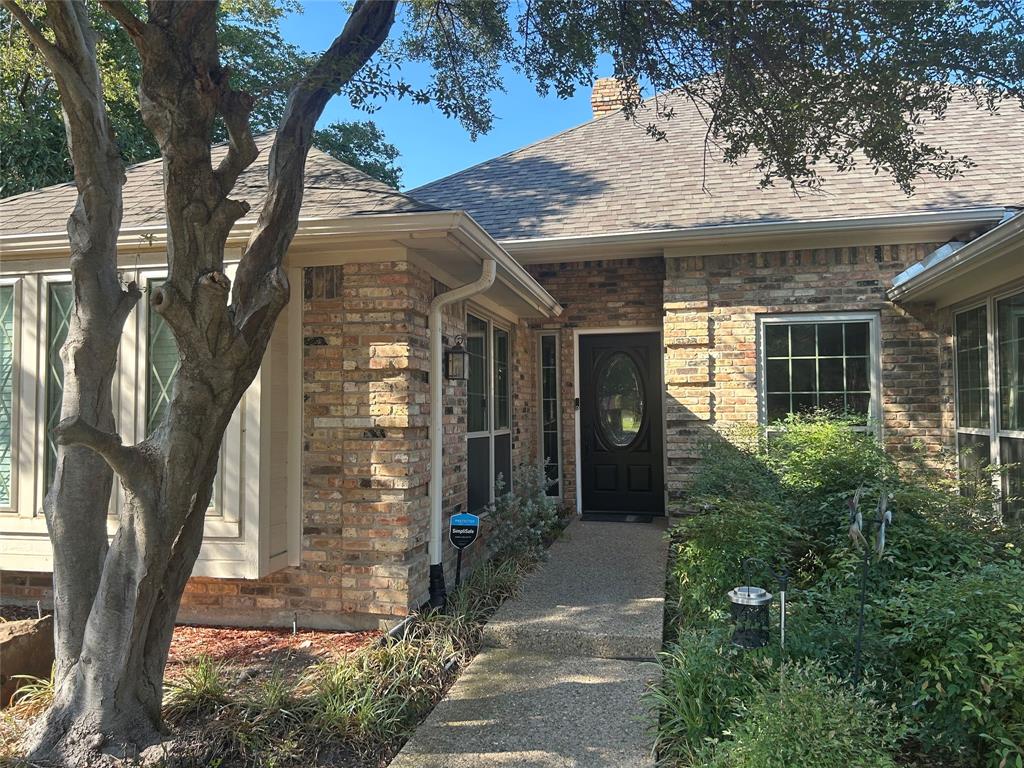 Brick exterior facade featuring a multi-gabled roofline, oval-insert front door, and concrete entryway path