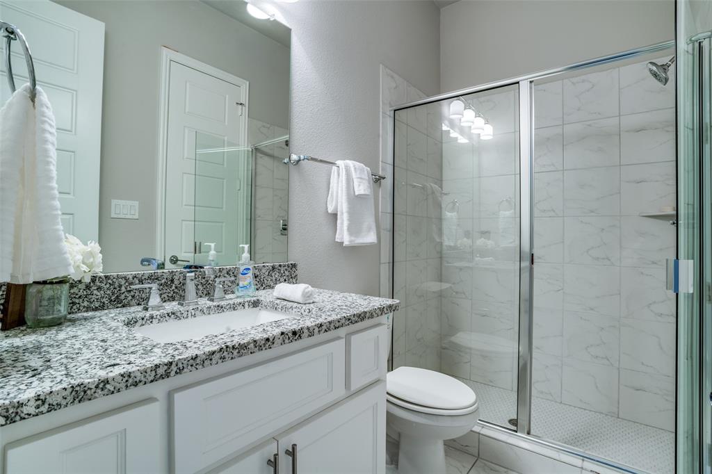 Downstairs bathroom featuring oversized vanity with granite countertops, walk in shower with enclosure.