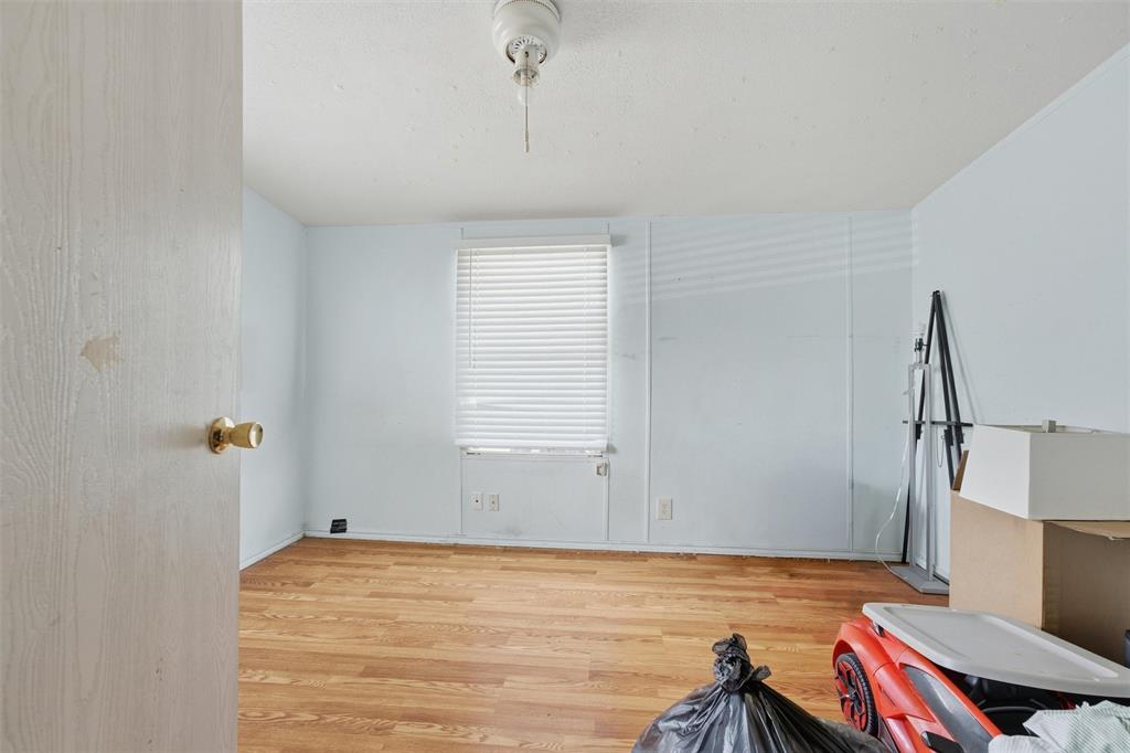 Room featuring wood-finish flooring, a central ceiling-mounted light fixture, and a window equipped with horizontal blinds